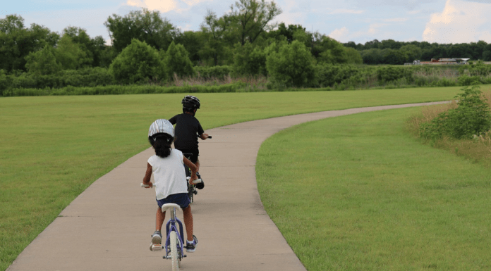 Two children riding bicycles on a paved path.