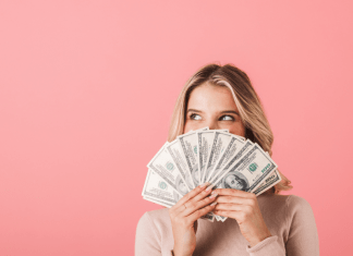 woman holds a fan of $100 bills in front of her face