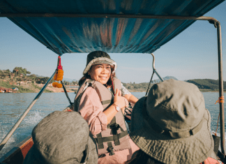 Two daughters look ahead at their mom looking back on them on a fishing boat in Southeast Asia.