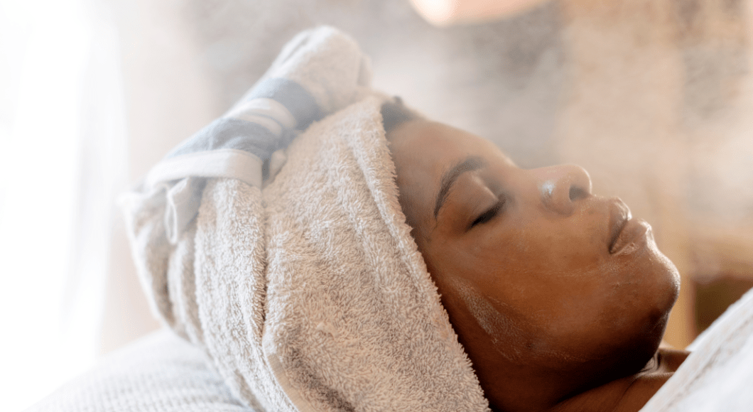 Woman receives a facial treatment with steam at the spa.