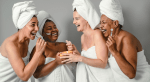 A group of women in towels and hair wraps laugh at the spa.