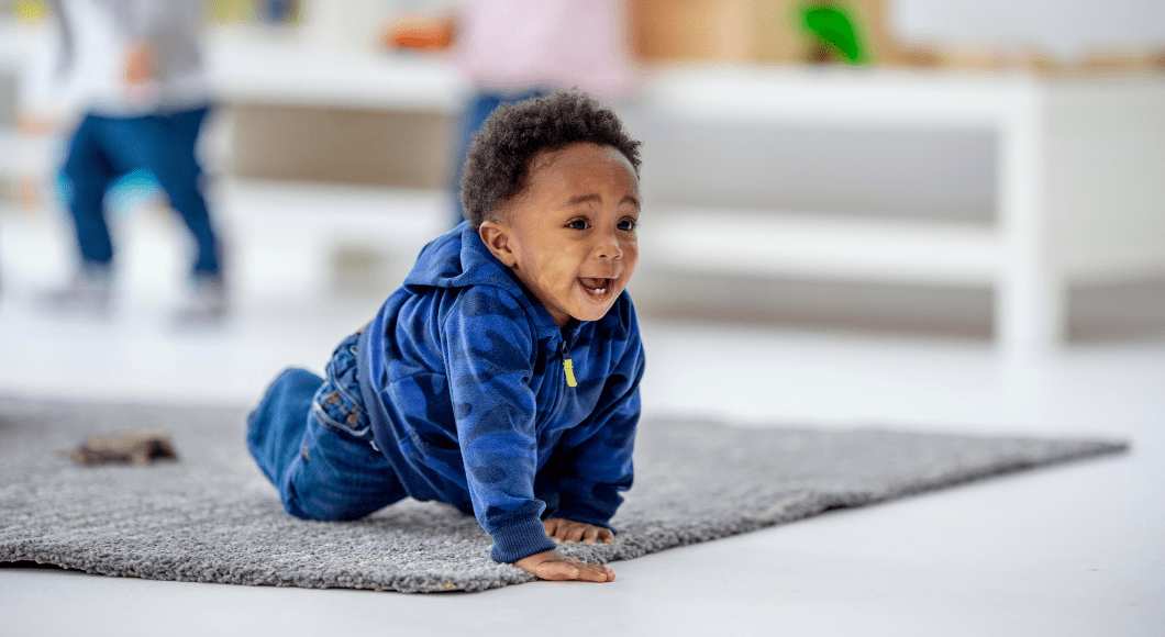 Happy baby boy crawls on the floor at daycare.
