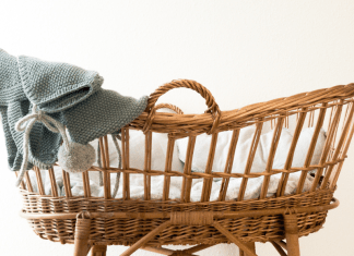 A wicker bassinet with a baby blanket draped over it