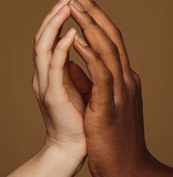 Hands of an interracial couple touch lovingly