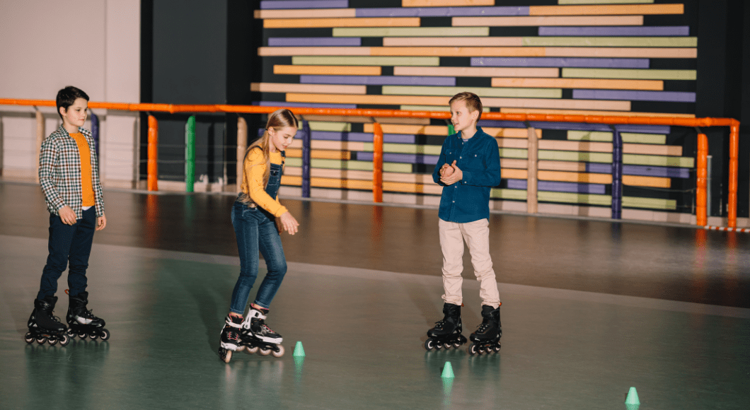 Three children indoor skating at roller rink.