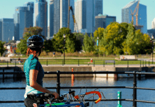 Woman wearing a helmet with bike overlooks city skyline