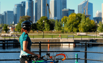 Woman wearing a helmet with bike overlooks city skyline