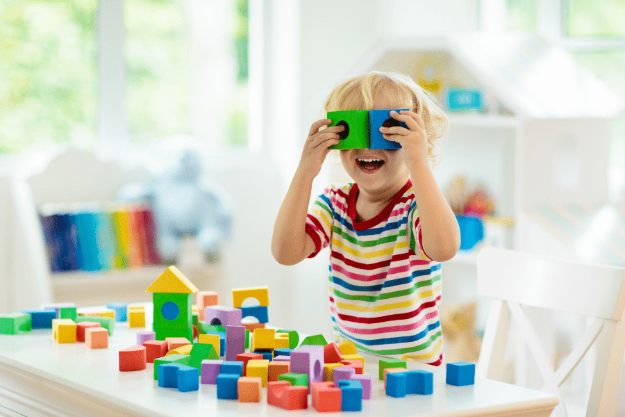 Child holds blocks to his eyes at an indoor play facility.