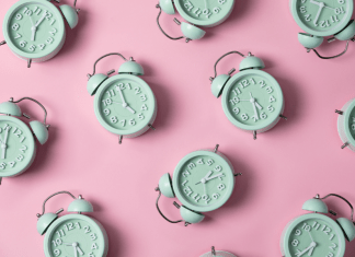 Green alarm clocks set to 5:00 and after on a pink background.