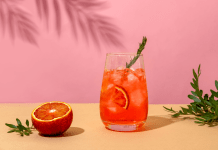 Negroni cocktail and a blood orange on a pink background