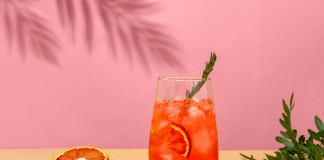 Negroni cocktail and a blood orange on a pink background