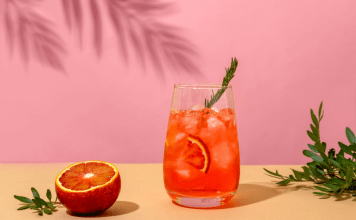 Negroni cocktail and a blood orange on a pink background