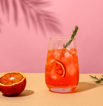 Negroni cocktail and a blood orange on a pink background