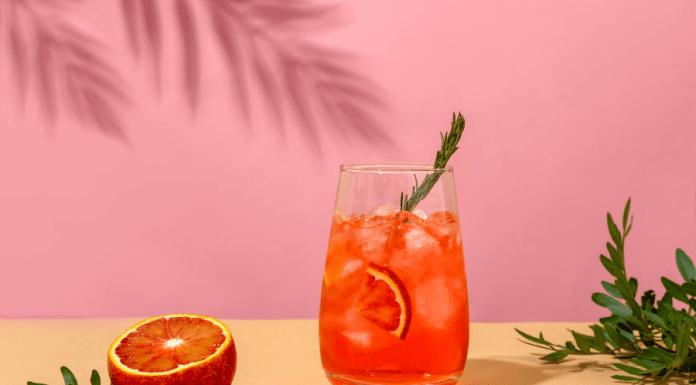 Negroni cocktail and a blood orange on a pink background