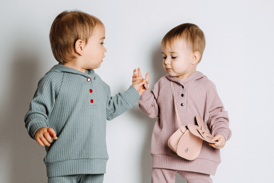 Toddlers wearing matching top and bottom ribbed sets, and the little girl has a mini purse.