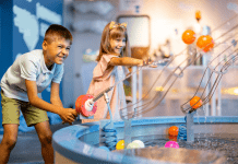 A boy and girl play with an interactive water machine inside a museum.