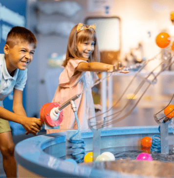 A boy and girl play with an interactive water machine inside a museum.