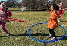 Little girls hula hoop in a field.