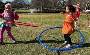 Little girls hula hoop in a field.