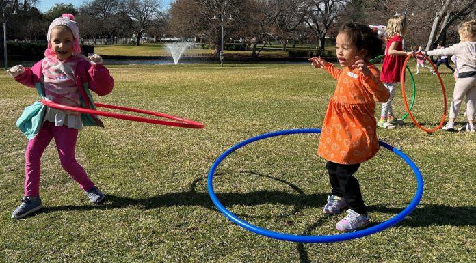 Little girls hula hoop in a field.